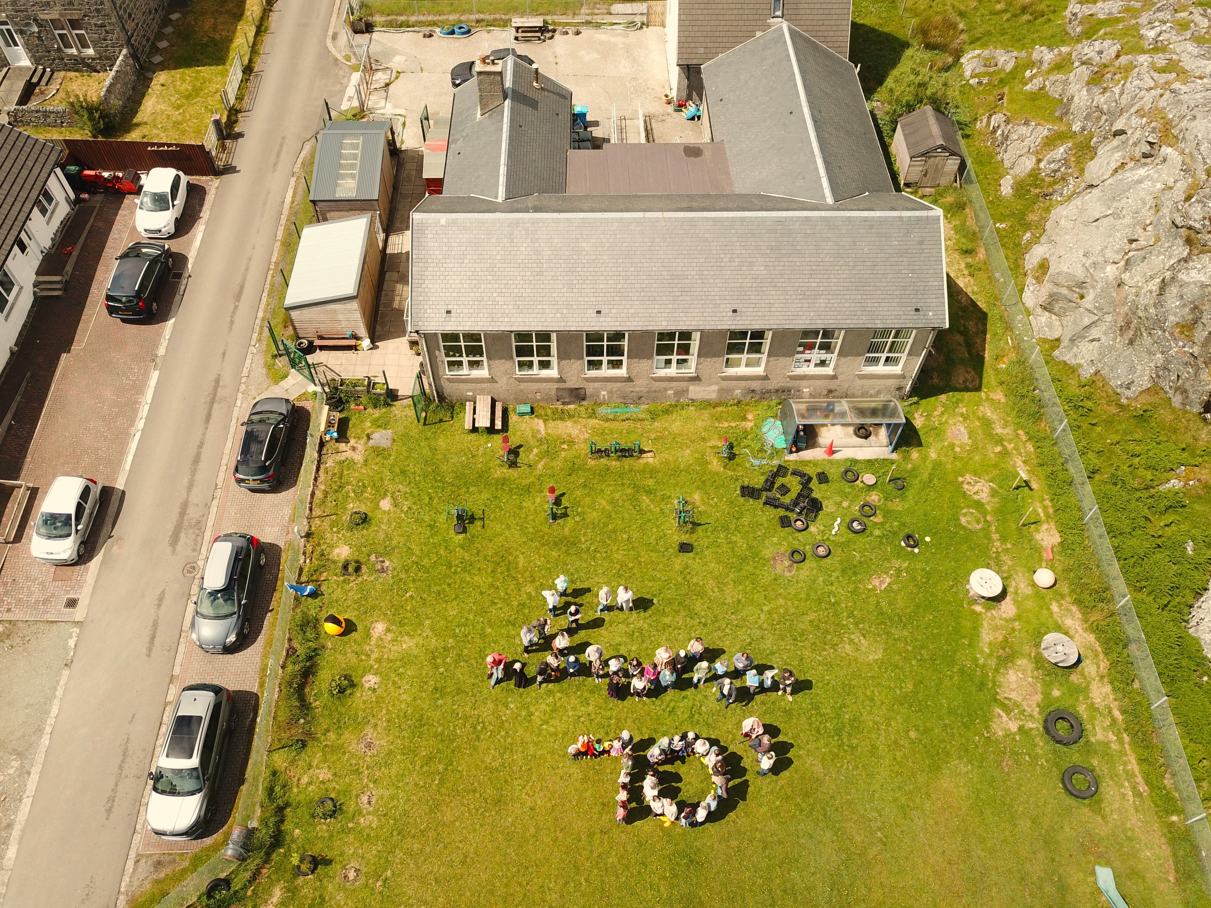 Aerial view of building with people in grounds spelling out 70